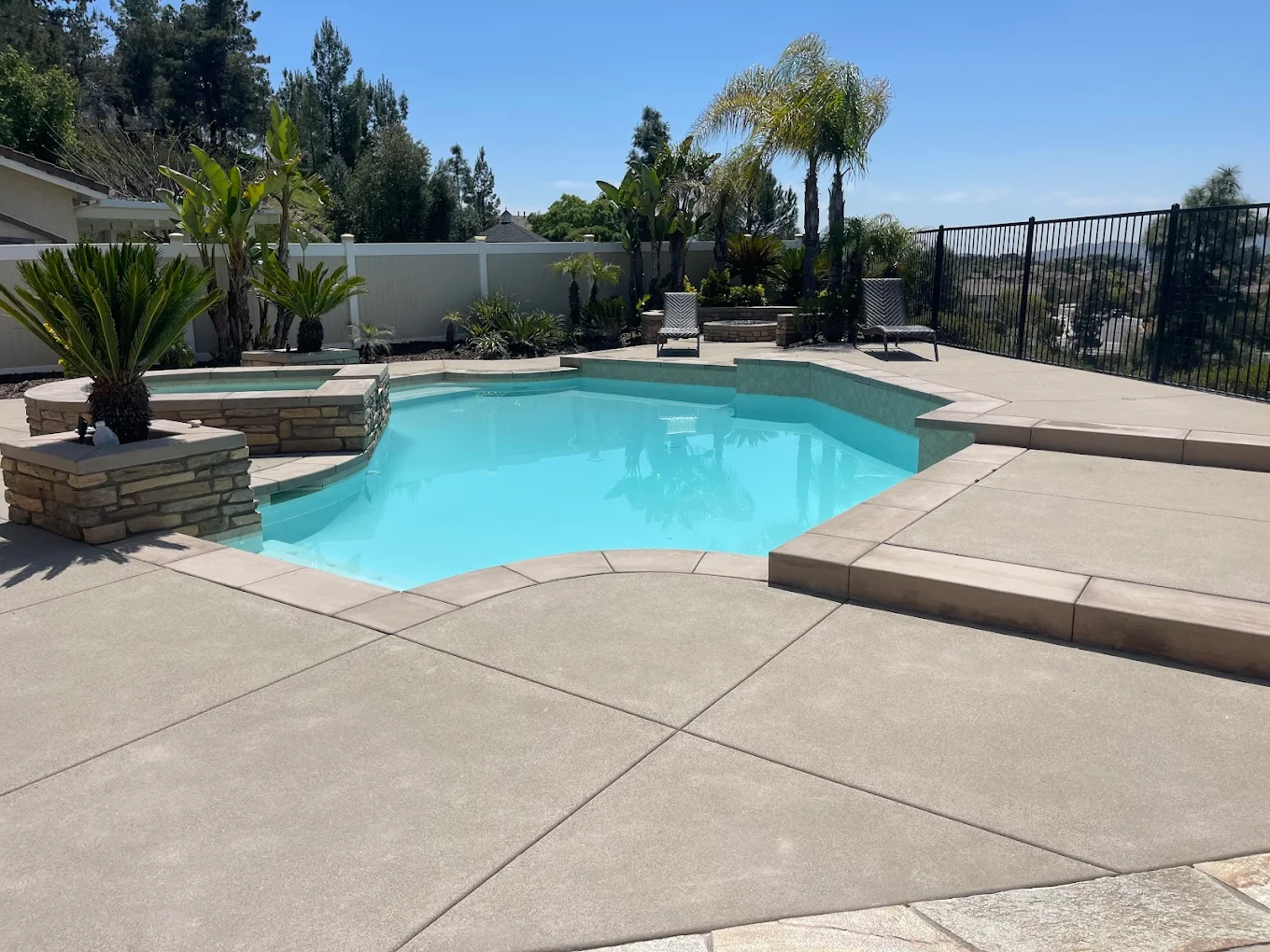 Clean finished backyard pool with patio and hillside view